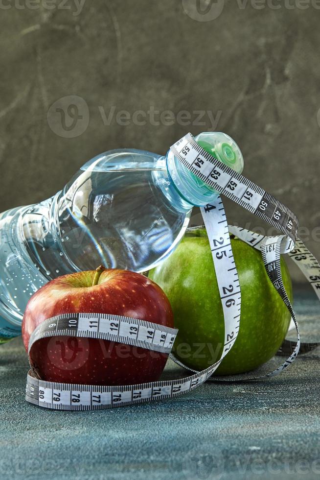 frukt och en flaska vatten med mätaren på en blå bakgrund foto