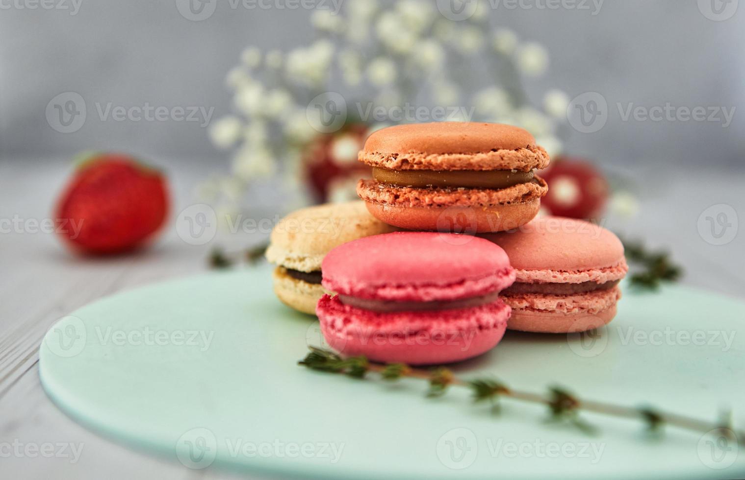 franska färgglada makroner. färgglada pastellkakor på en ljus bakgrund med färska jordgubbar. koncept mjukt fokus. foto