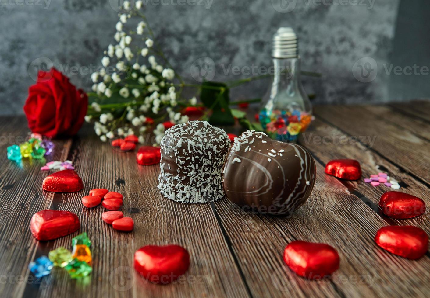 romantisk stilleben röd roschoklad i form av hjärtan och chokladkakor på träbakgrund foto