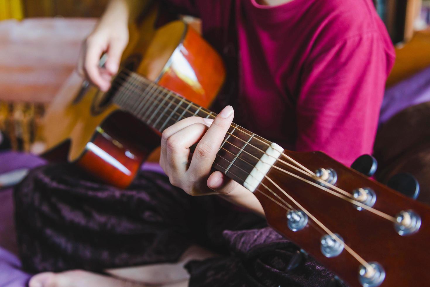 närbild av manlig musikalisk artist som spelar på brun klassisk gitarr. foto