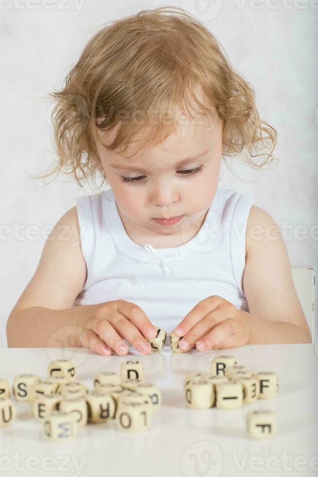små flicka komponerar ord från brev. närbild foto
