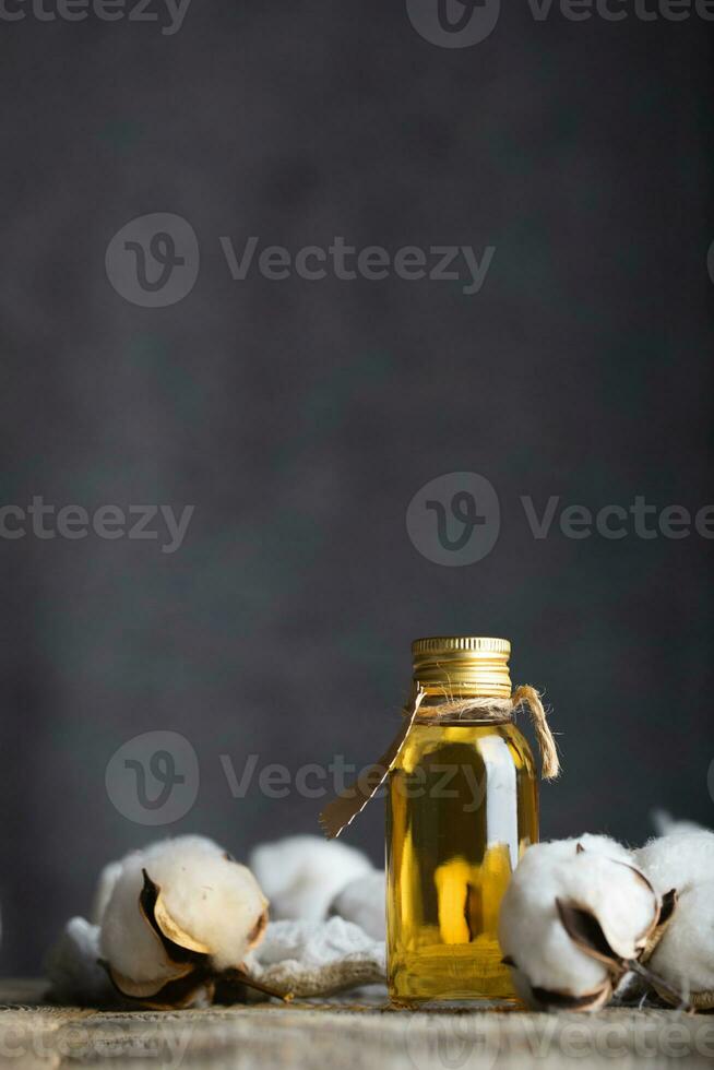 bomullsfrö olja i en glas flaska på en trä- yta. foto