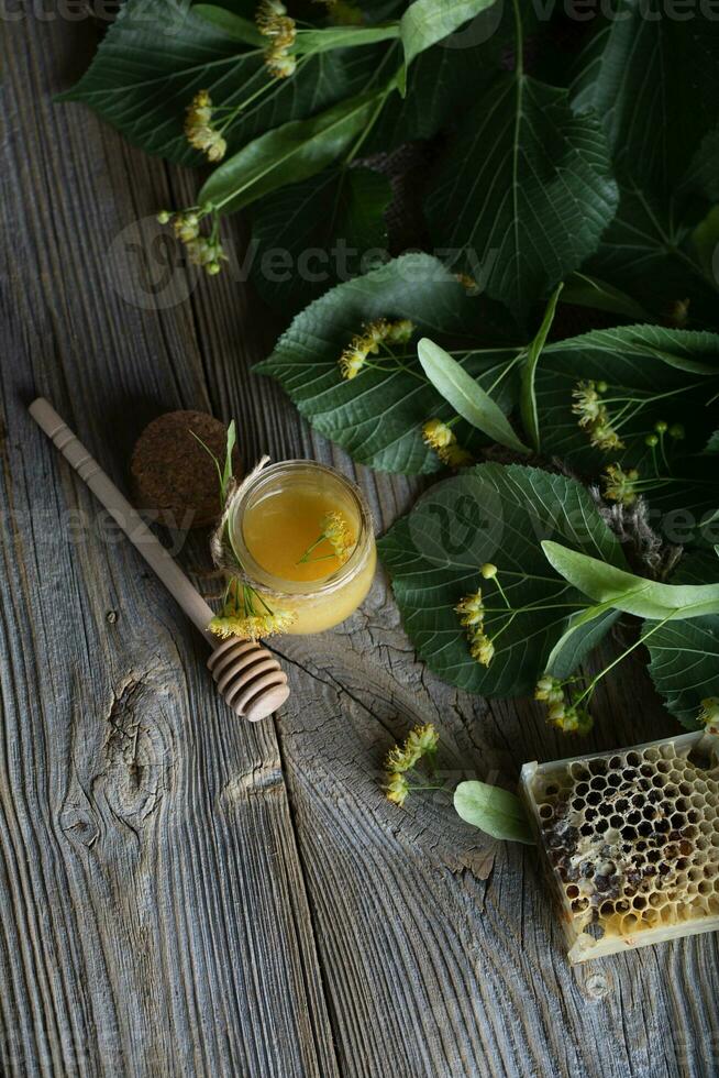 lind blommar honung i en glas flaska på en trä- yta. foto