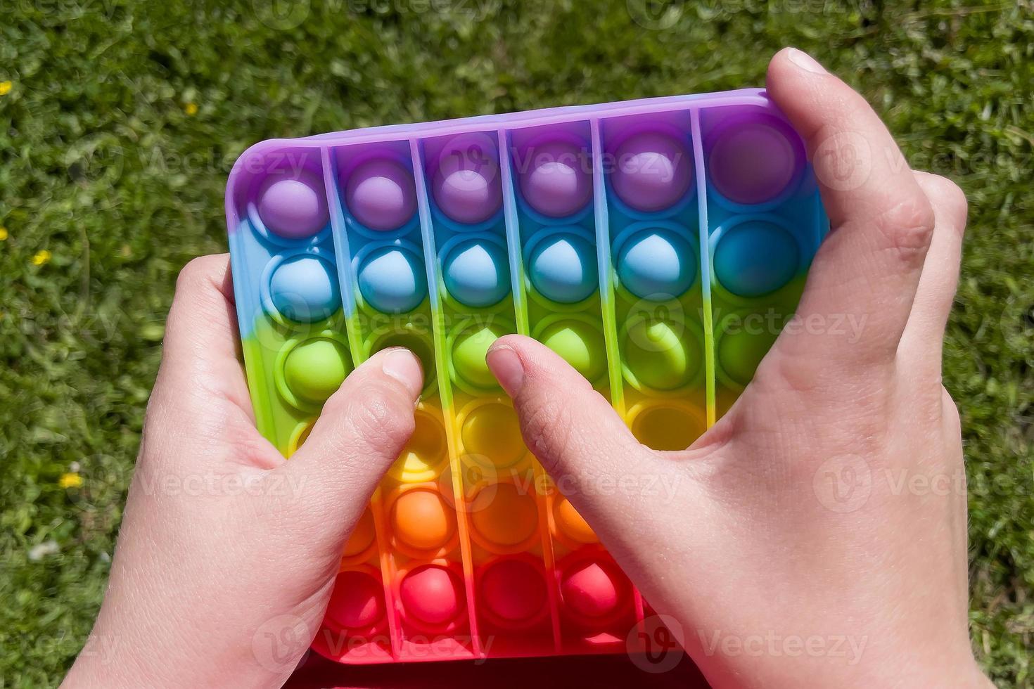 färgglada anti-stress sensoriska fidget push pop det leksak i barns händer foto
