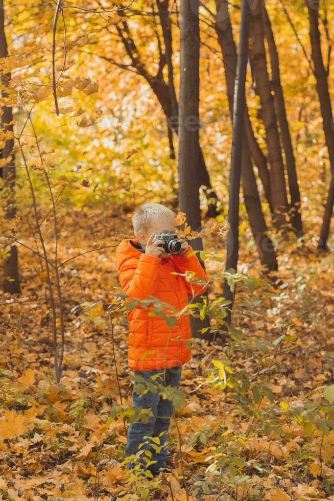 pojke med retro kamera tar bilder utomhus- i höst natur. fritid och fotografer begrepp foto