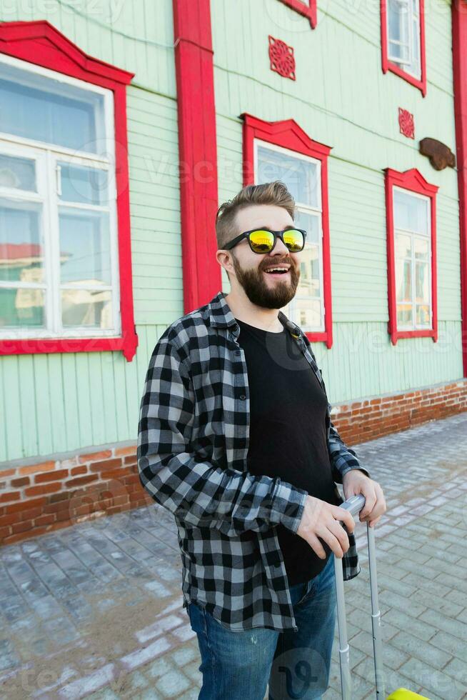 porträtt av Lycklig resa man med resväska stående nära de byggnad i stad. foto