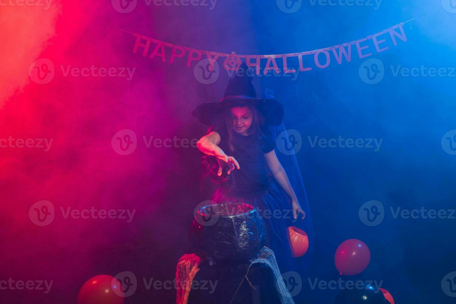 barn flicka häxa framställning en trolldryck i de kittel på halloween högtider. foto
