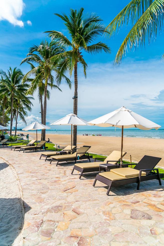 vacker tropisk strand och hav med paraply och stol runt poolen i hotellresorten foto