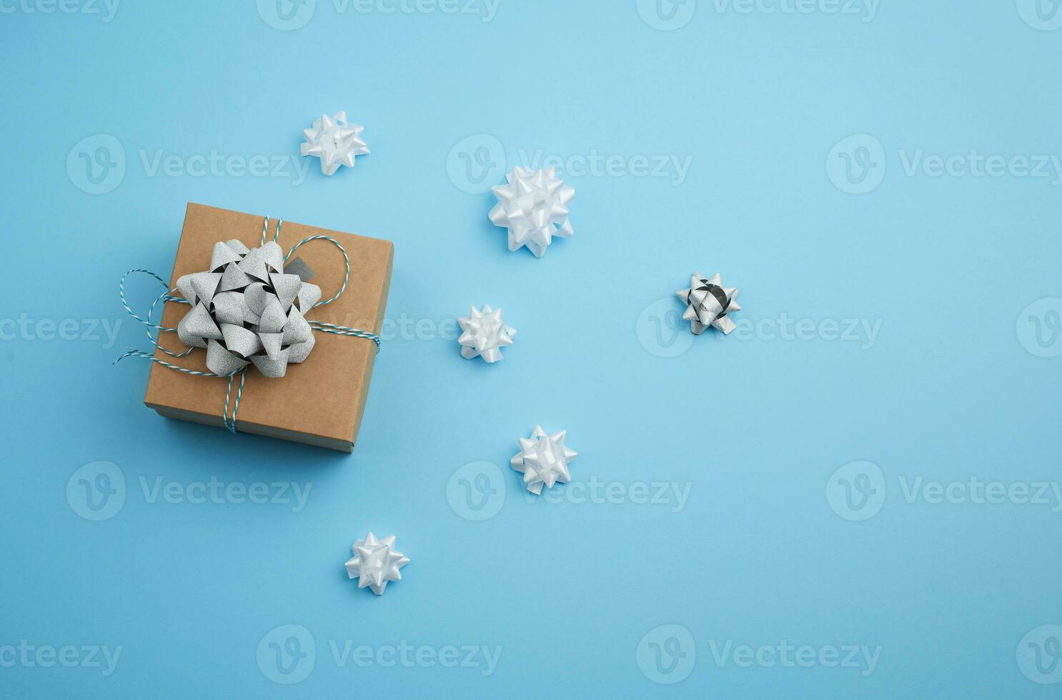 brun fyrkant låda med en gåva bunden band med en rosett på en blå bakgrund foto