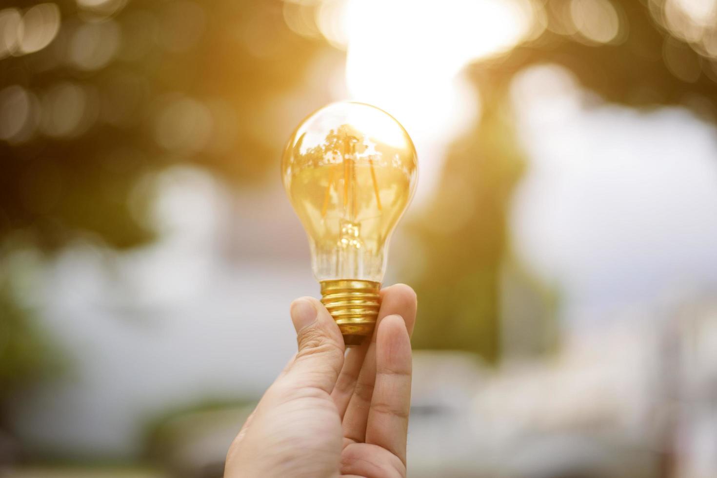 närbild handen håller glödlampa, rädda jorden koncept foto