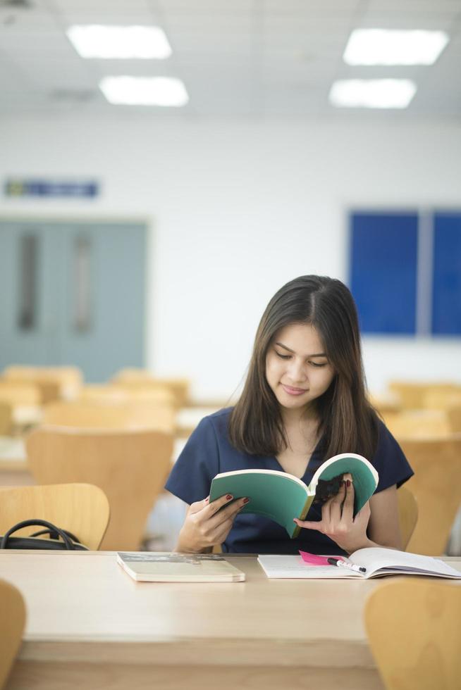 vackra kvinnliga asiatiska universitetsstudenter i biblioteket foto