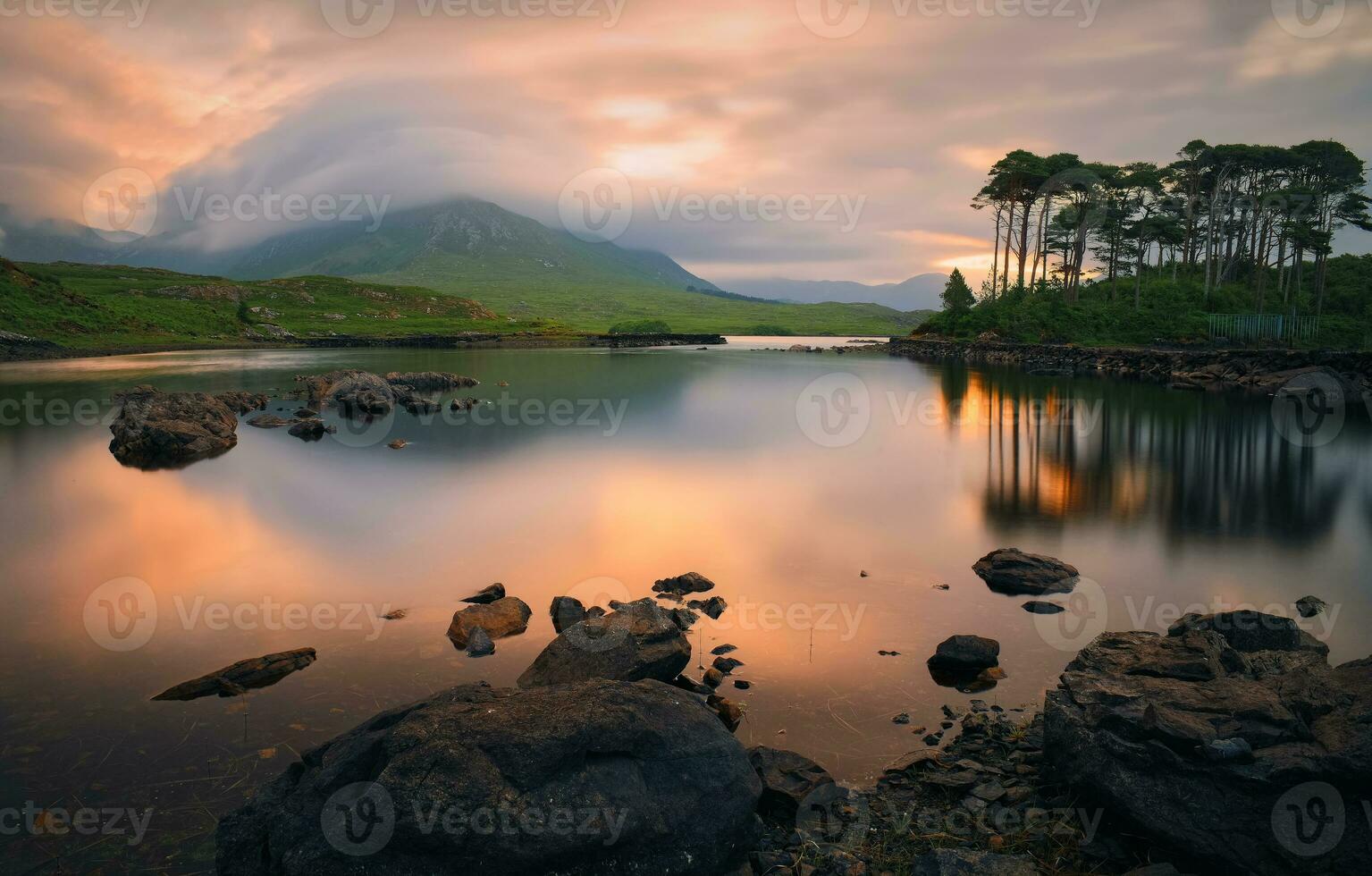 dramatisk molnig sjön landskap soluppgång landskap av tolv tallar ö reflekterad i vatten omgiven förbi bergen på derryclare, connemara nationell parkera i grevskap galway, irland foto