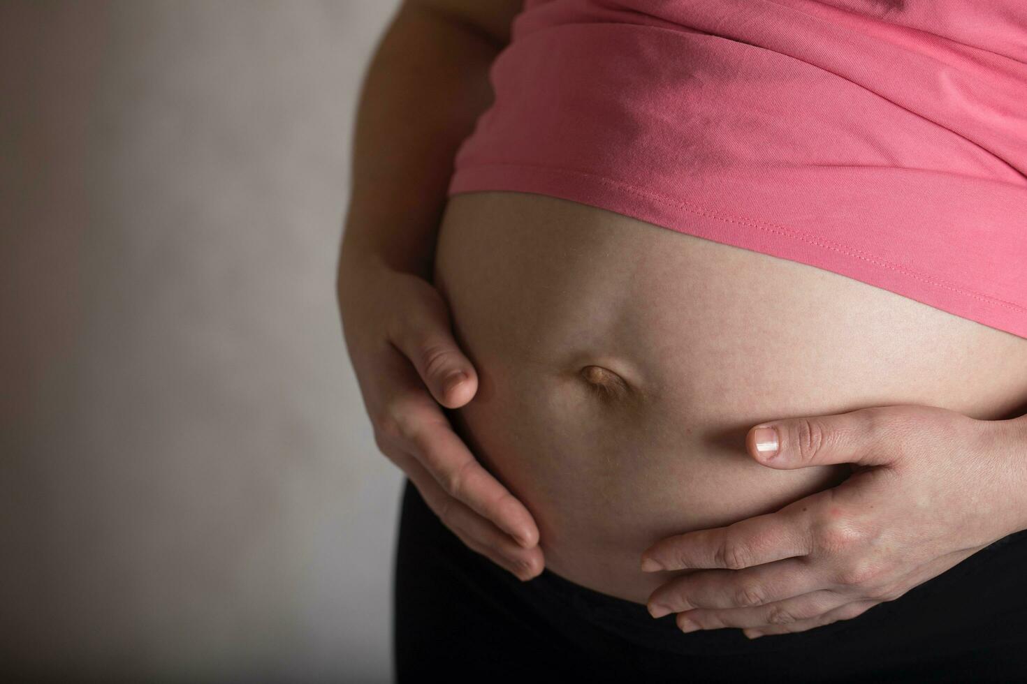 ung gravid kvinna finputsning henne mage. dramatisk ljus. foto