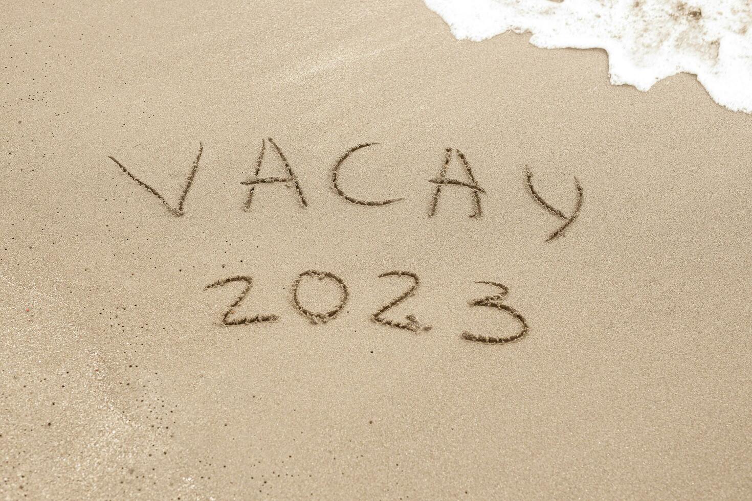 ord vacay 2023 skriven på de sand foto