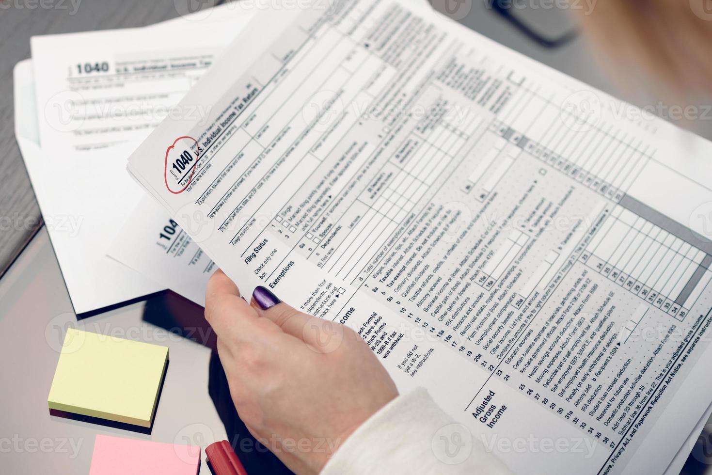 kvinnan fyller i skatteformuläret och arbetar med skattedokument. blankett 1040 individuell inkomstdeklarationsblankett. USA: s skatteformulär. amerikanska blanketter. skattetid. foto