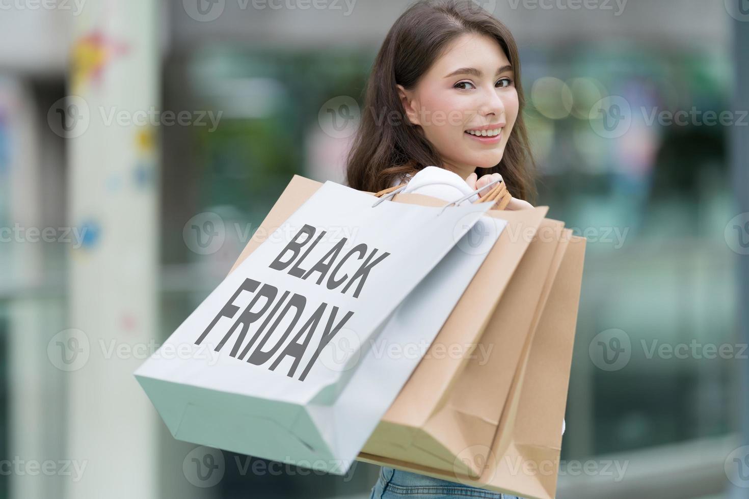 svart fredagskoncept, kvinna som håller många påsar och ler i butiken under shoppingprocessen foto