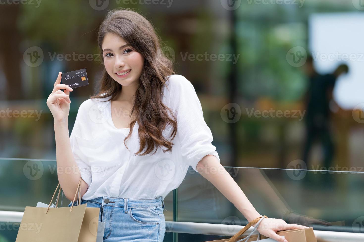 svart fredag koncept, kvinna som håller många shoppingkassar med kreditkort och ler foto
