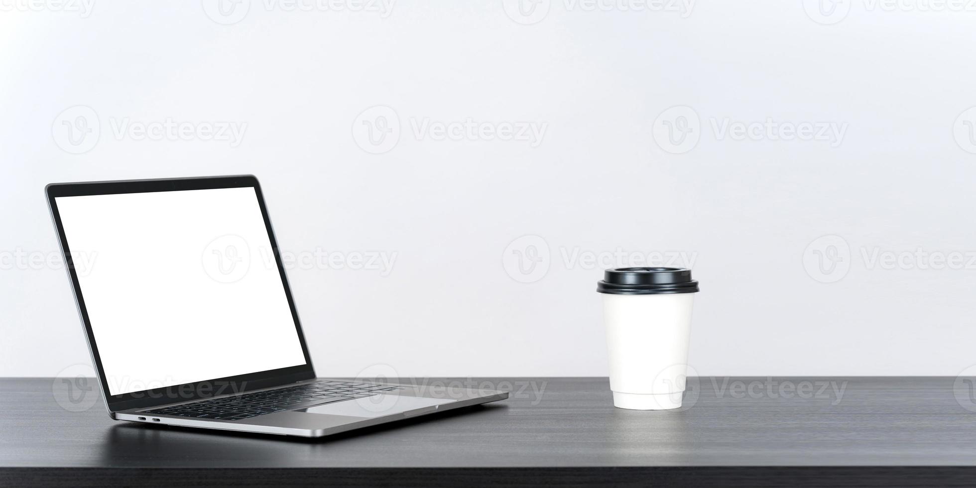 bärbar dator tom vit skärm på bordet med papper kaffekopp foto