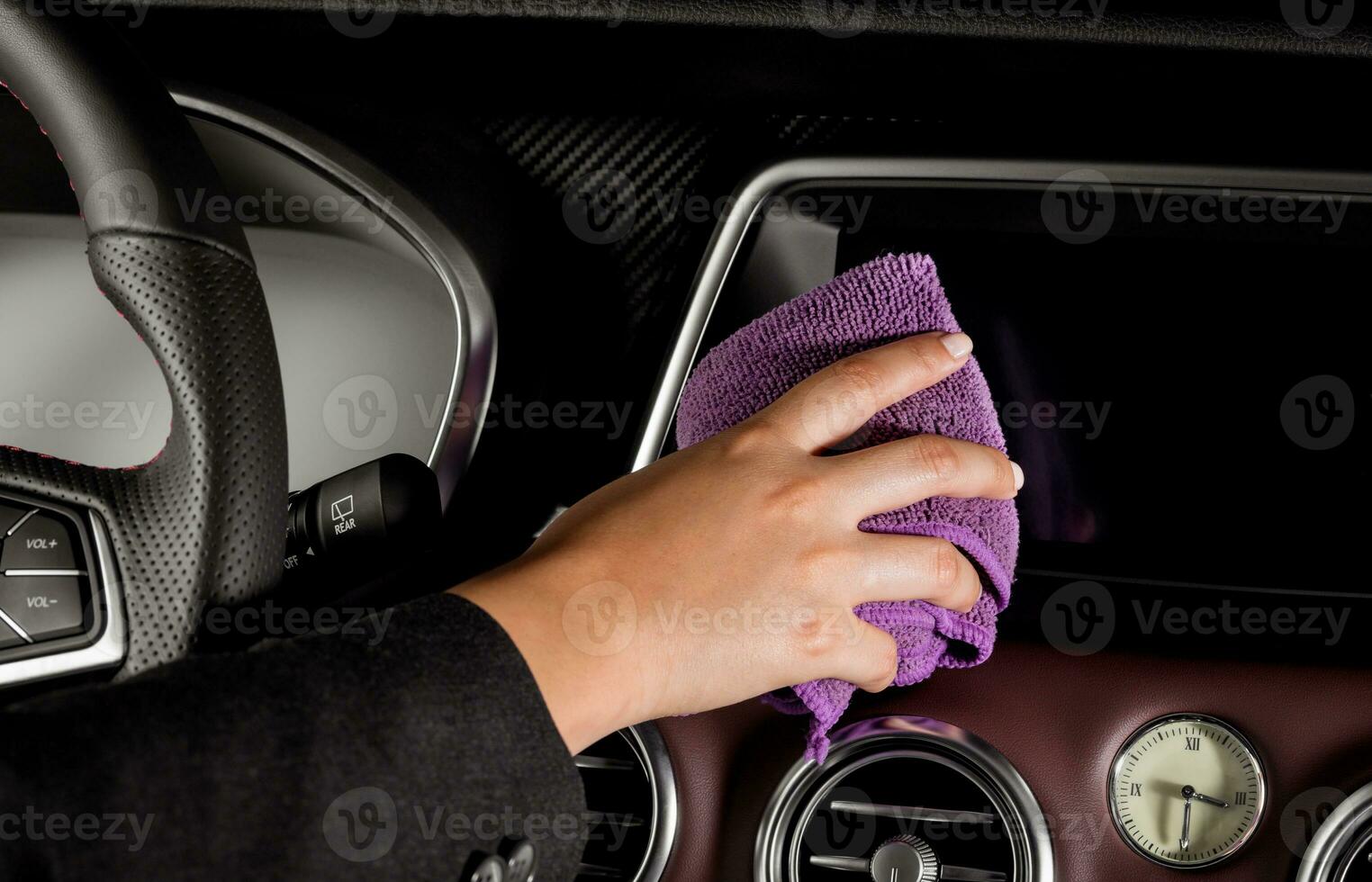 en ung kvinnas hand med en lila mikrofiber trasa rengöring de skärm inuti en lyxig bil foto