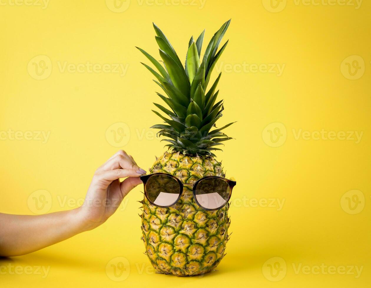 saftig ananas med solglasögon, sommar semester begrepp, kvinna hand, gul bakgrund - näringsrik frukt. foto