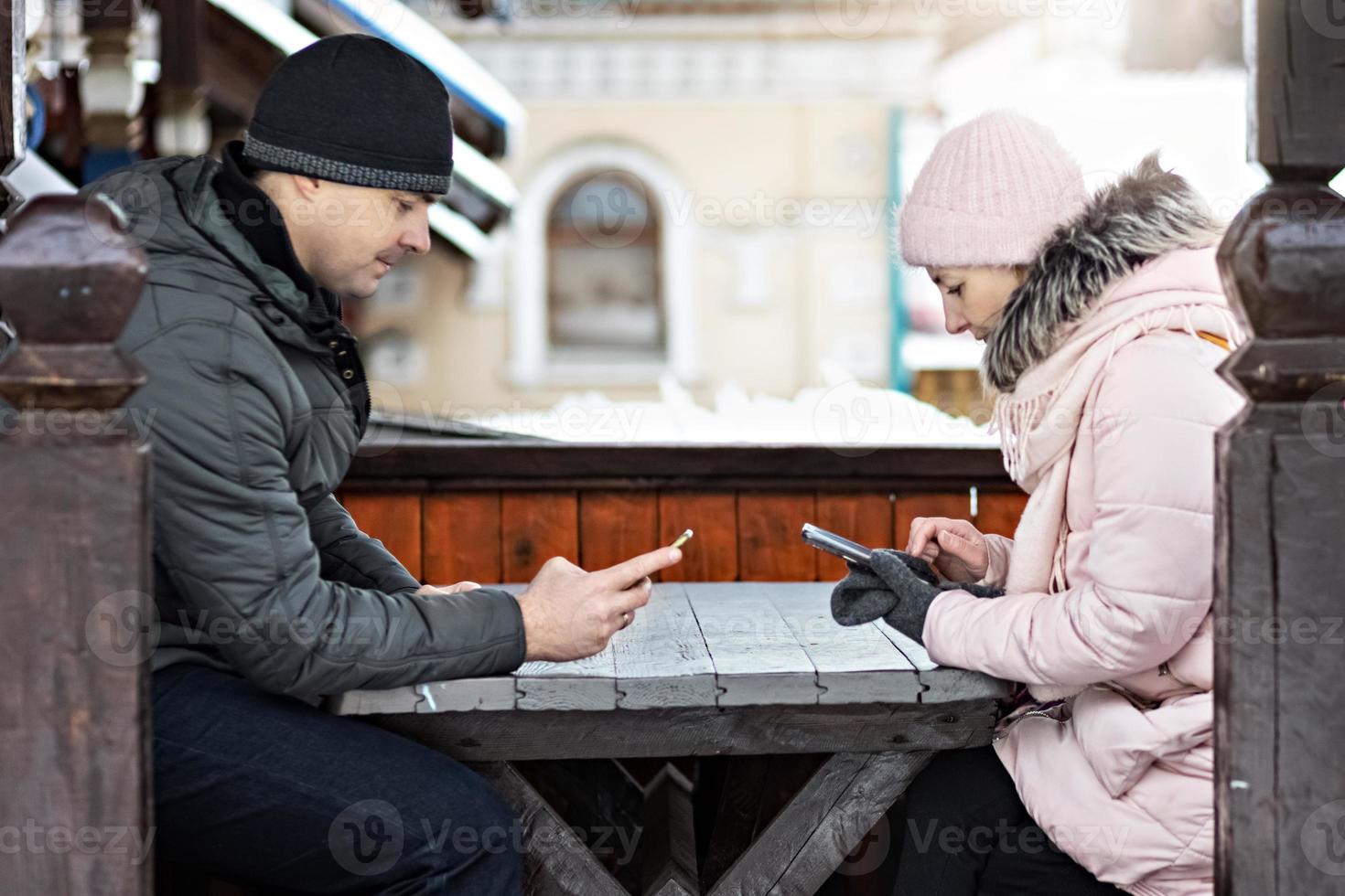 ett par väntar på sin beställning till lunch på ett gatukafé, sms via telefon. kommunikation med människor på en smartphone. foto