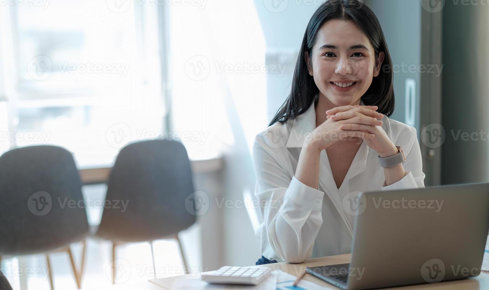 vacker ung asiatisk flicka som arbetar på ett kontor med en bärbar dator. foto
