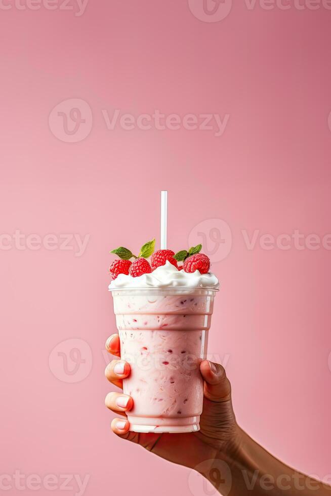 hand innehav milkshake med vispad grädde och hand innehav milkshake med vispad grädde och hallon på rosa bakgrund på rosa bakgrund foto