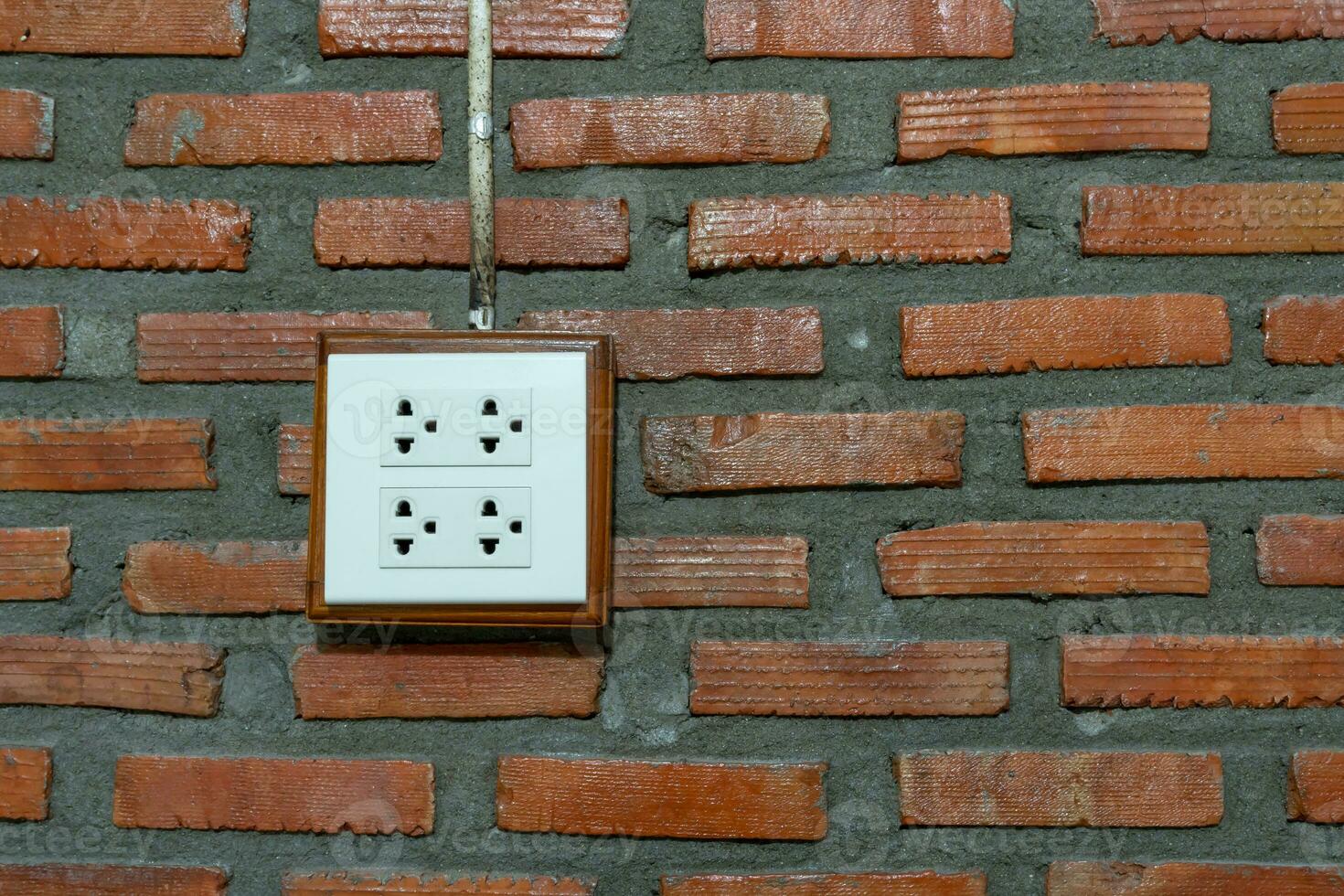 vit uttag installerad på orange tegel vägg i hotell eller tillflykt rum. foto