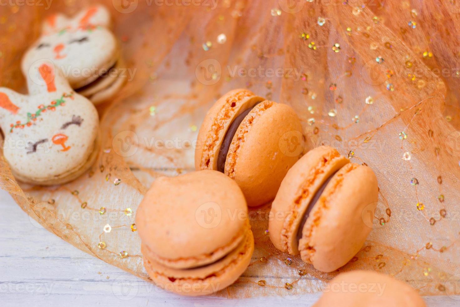 orange makron med chokladpåfyllning och påskkaninmakron, på orange tyllbakgrund foto