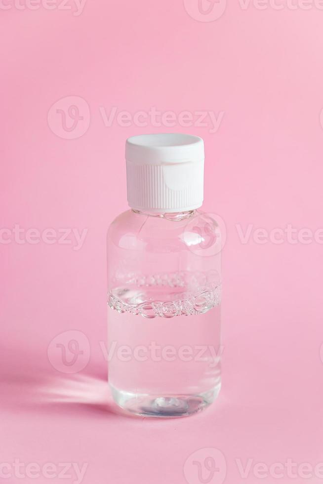 flaska med micellärt rengöringsvatten på rosa bakgrund. hudvård koncept. foto