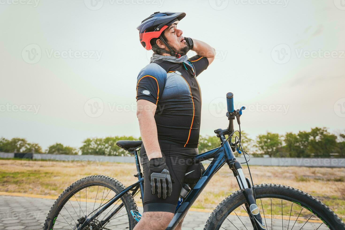 manlig cyklist med nacke smärta utomhus. sportig cyklist har nacke smärta medan ridning en cykel foto