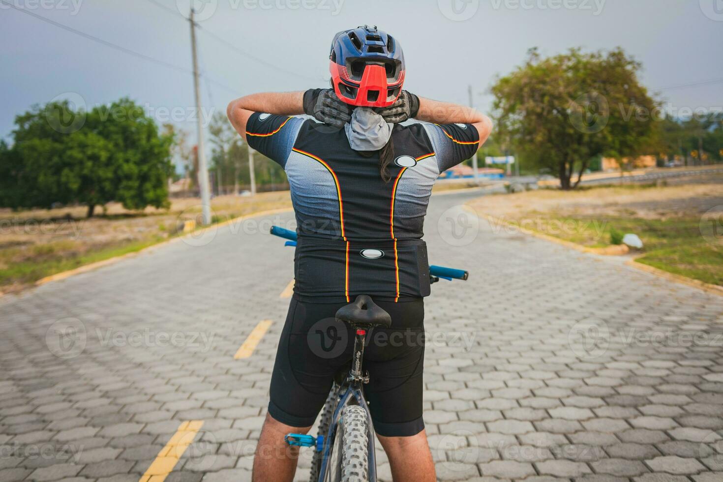 bak- se av en cyklist med nacke smärta med de cykel. tillbaka se av en cyklist man har nacke smärta medan ridning en cykel foto