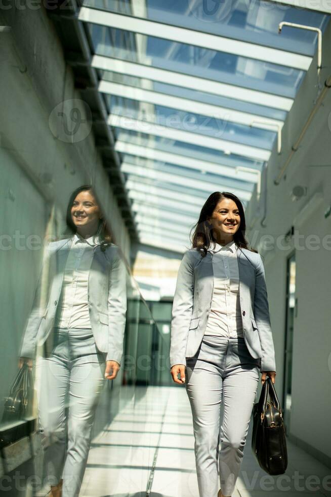 Söt ung företag kvinna gående med portfölj i de kontor hall foto