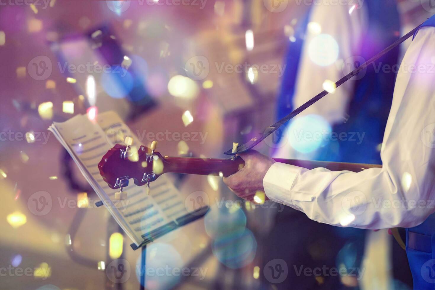 musikalisk händelse. händer av en musiker med en gitarr i främre av en nom i ljus konfetti. foto