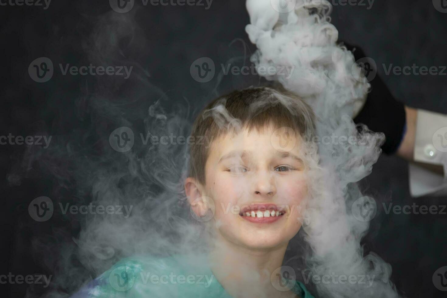 de barn är en deltagare i vetenskaplig experiment. en pojke i flytande kväve rök. foto