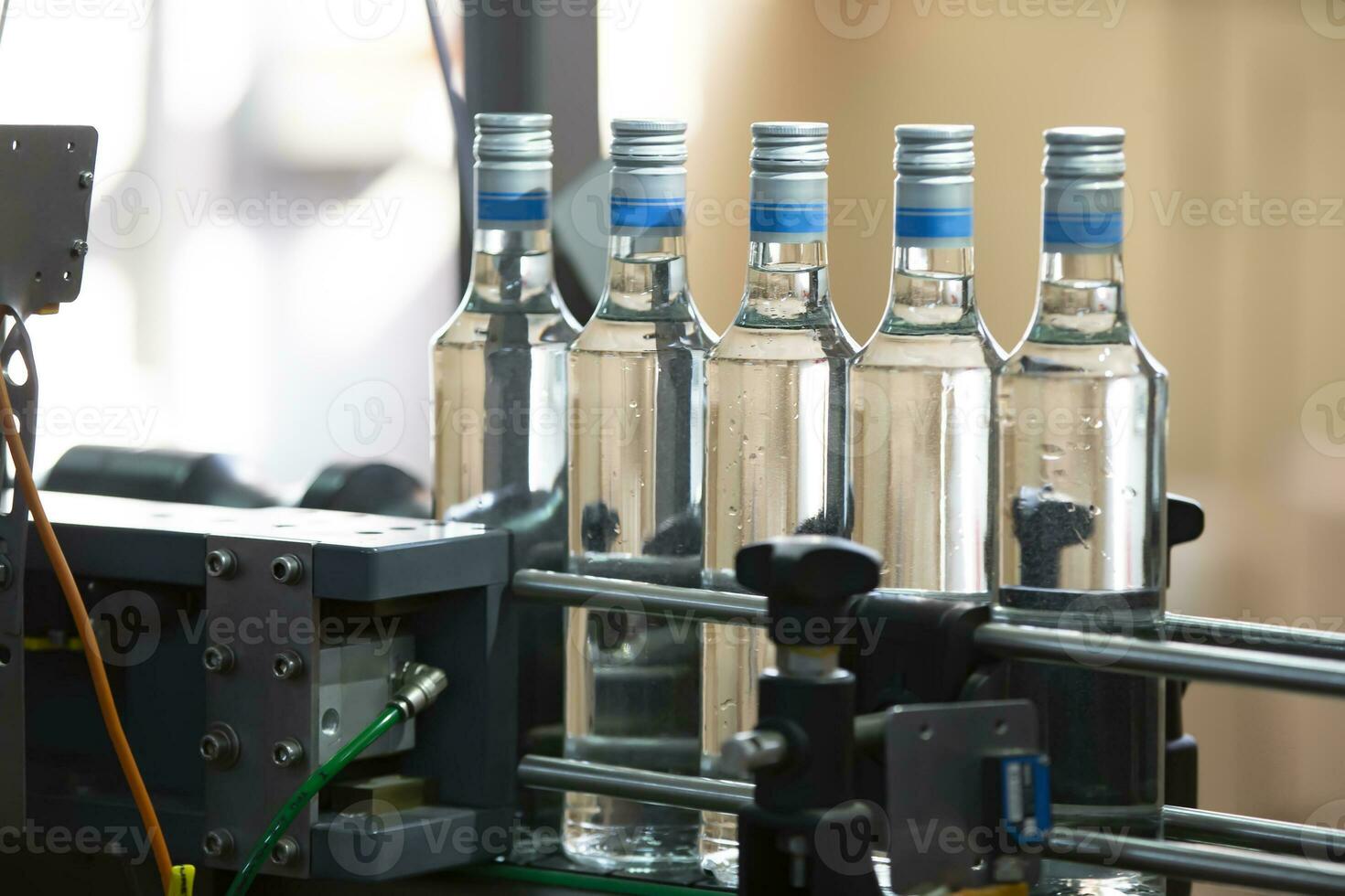 en lång rad av glas flaskor på en transportband bälte. produktion av alkoholhaltig drycker. foto