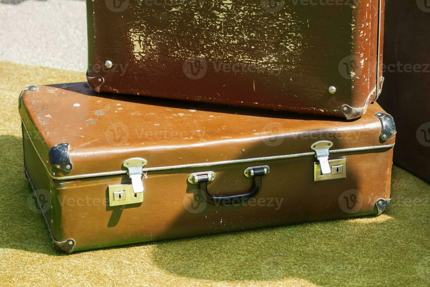 gammal sjaskig brun resväskor på en grön yta. foto