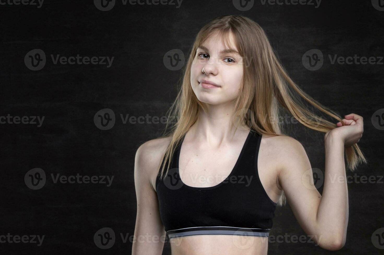 Tonårs flicka i en sporter skjorta på en mörk bakgrund. foto