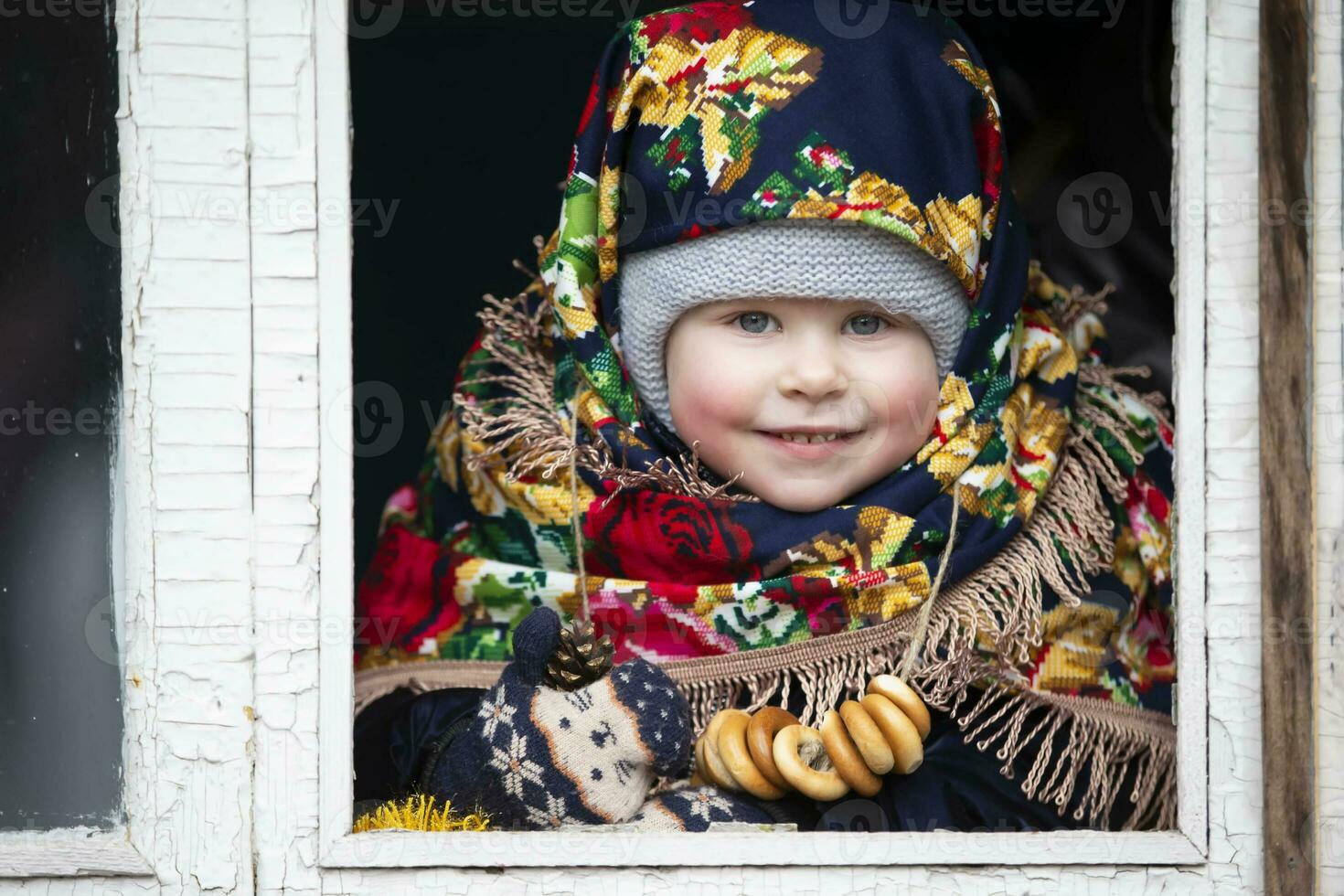 en liten flicka i en ryska slöja med bagels på de maslenitsa Semester. foto