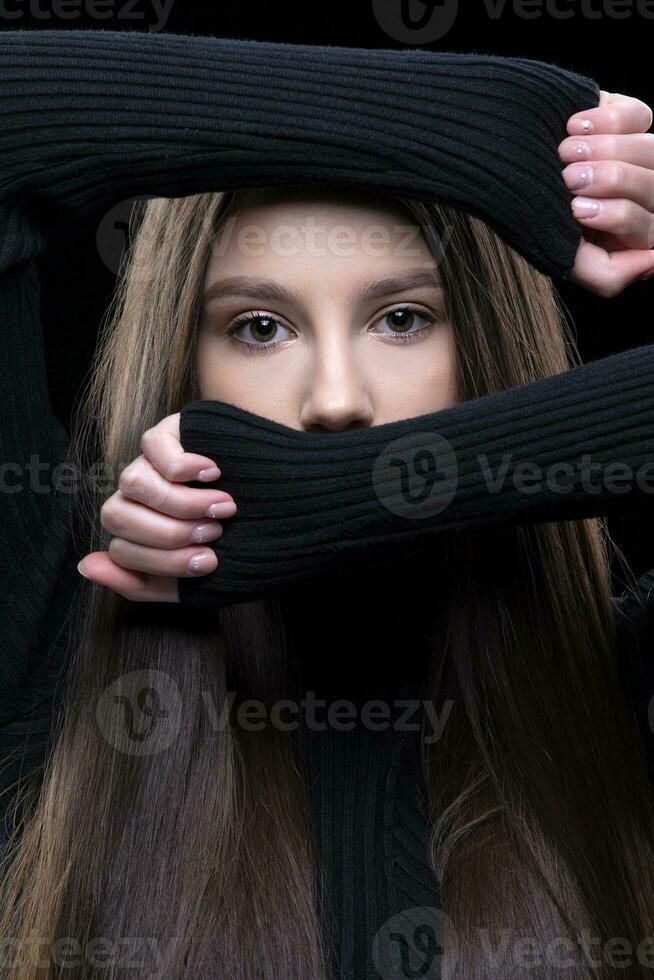 en skön brunett flicka täckt henne ansikte med henne händer, lämnar endast henne ögon. foto