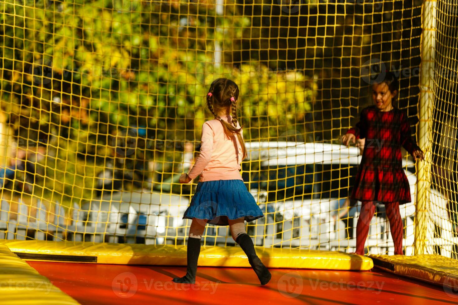 Lycklig skola flicka Hoppar på trampolin i de höst parkera foto