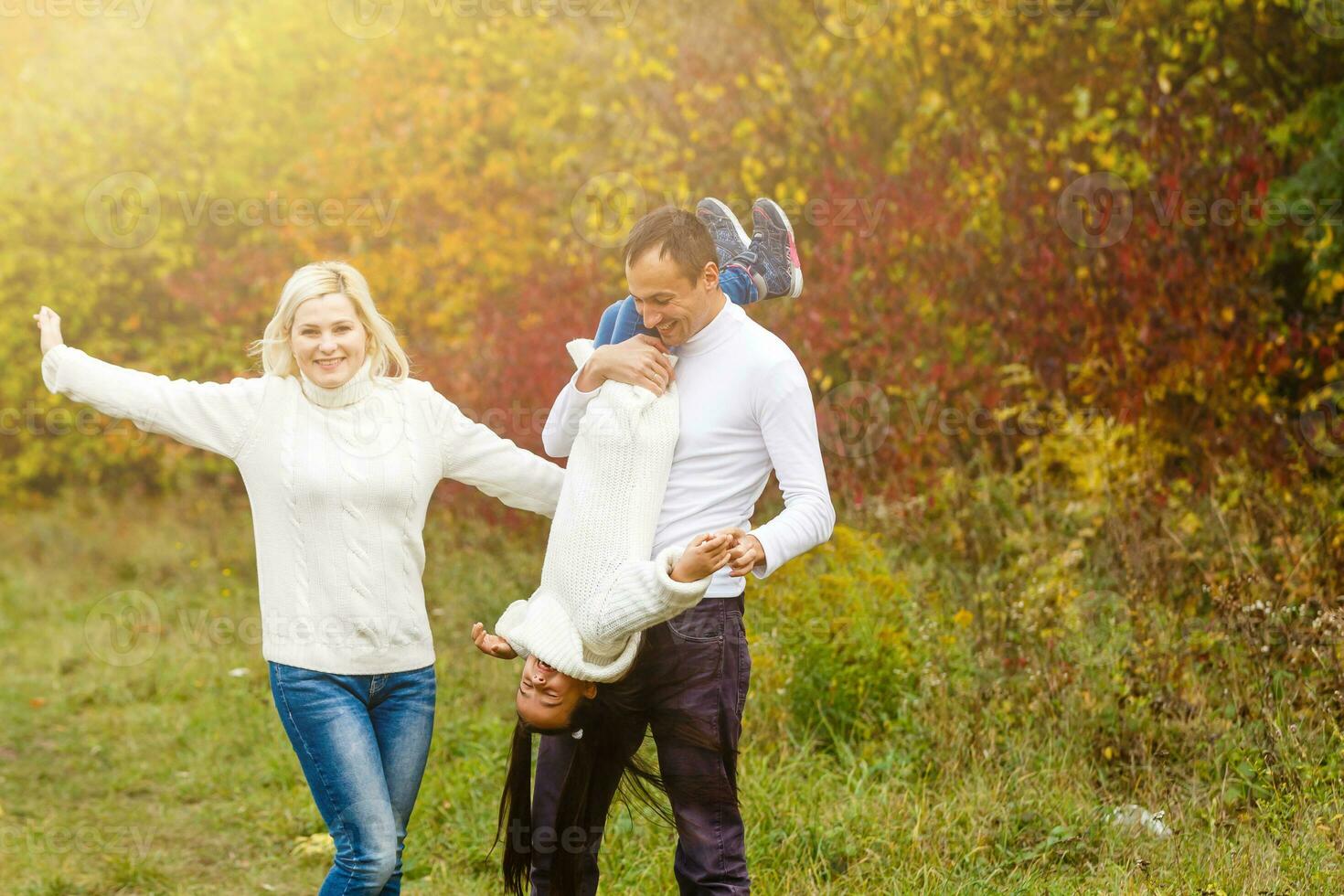 bild av härlig familj i höst parkera, ung föräldrar med trevlig förtjusande dotter spelar utomhus, ha roligt på bakgård i falla, Lycklig familj njut av höstlig natur foto