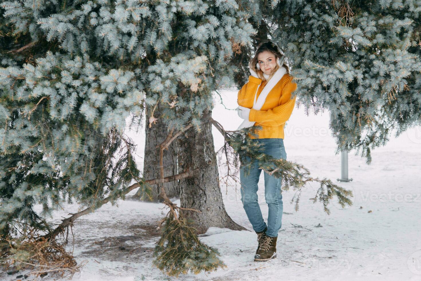 tonåring blond i en gul Tröja utanför i vinter. en Tonårs flicka på en promenad i vinter- kläder i en snöig skog foto