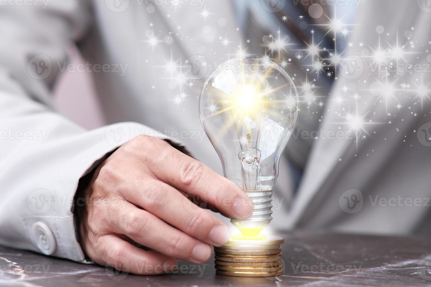 affärsman som håller glödlampan med mynt och affärsidéikoncept foto