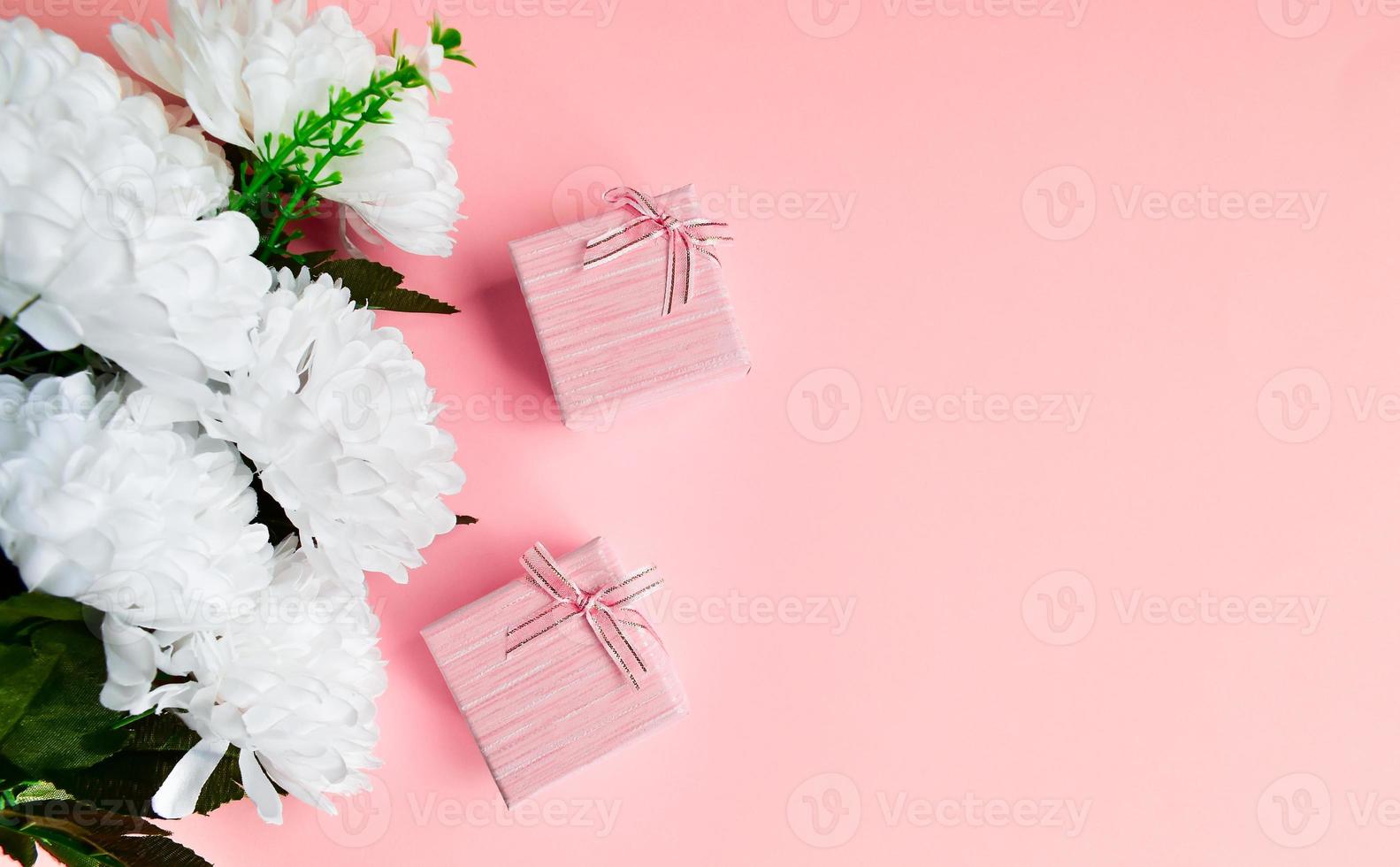 två rosa presentask med vit bukett blommor. foto