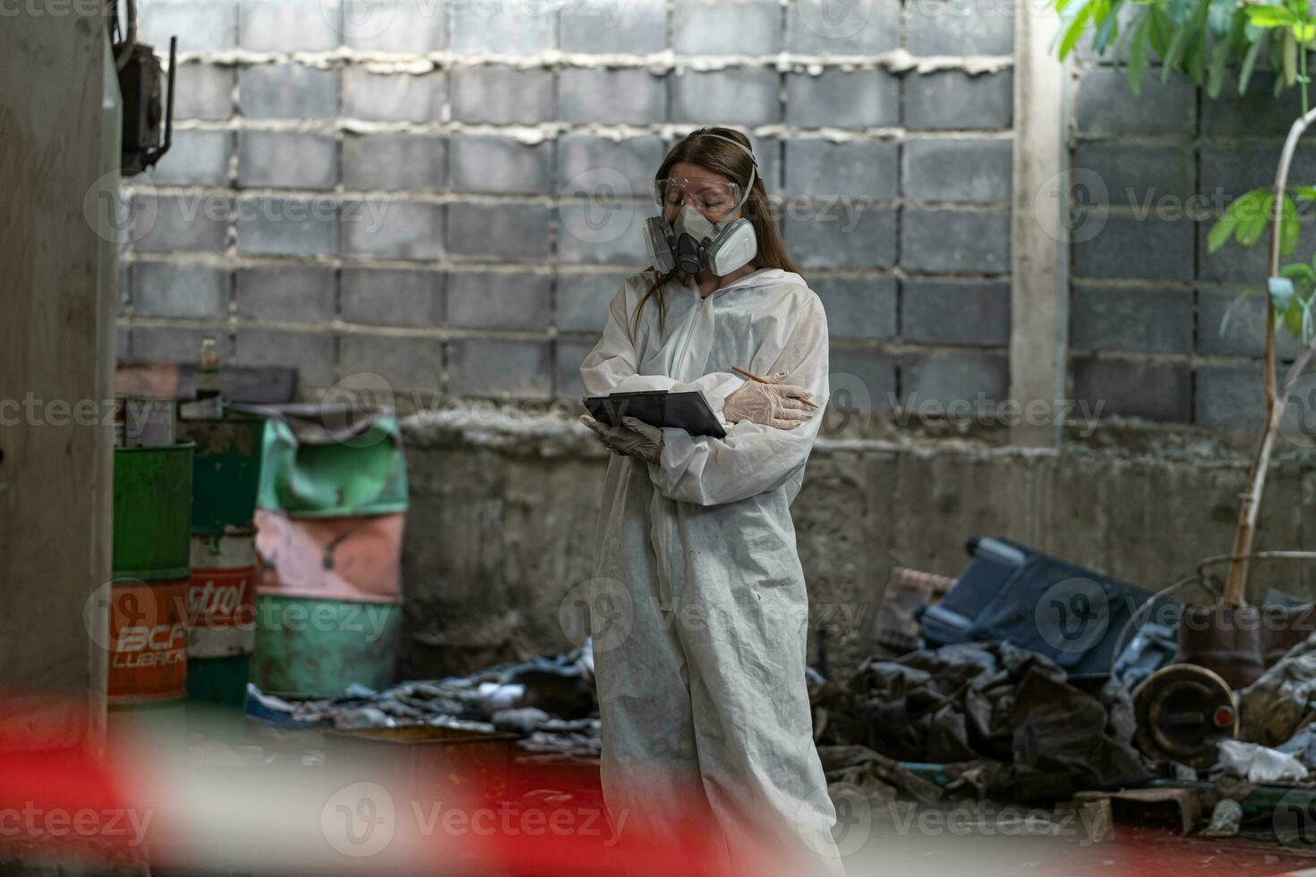 nödsituation förorening fabrik begrepp. kvinna kemist bär ppe och gas mask inspekterande olja på fabrik golv foto