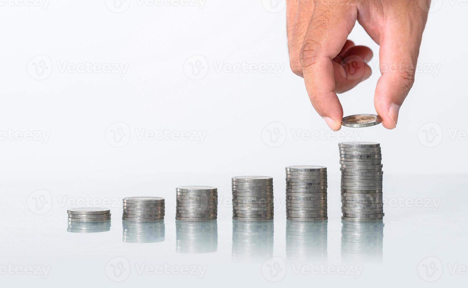 begreppet att spara pengar, hand sätta pengar mynt stack växer på vit bakgrund foto