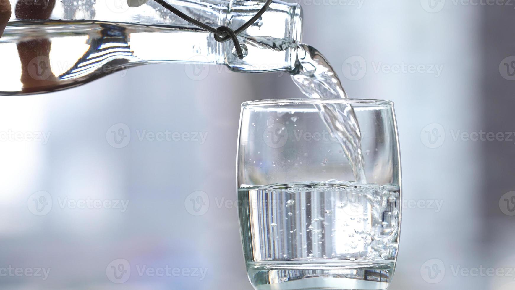 drick vatten som häller i glas på bordet foto