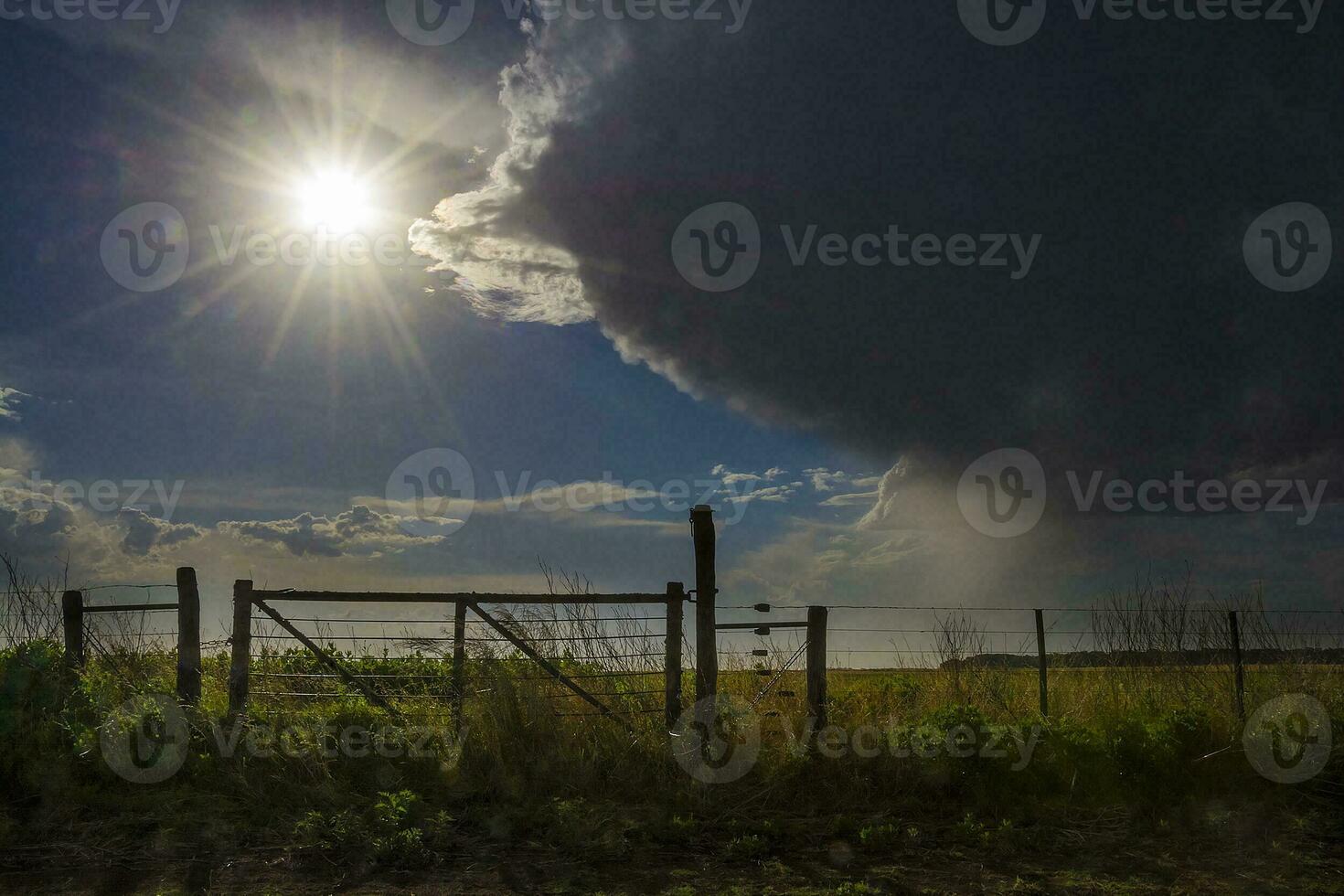 en mörk moln över en fält med en staket foto