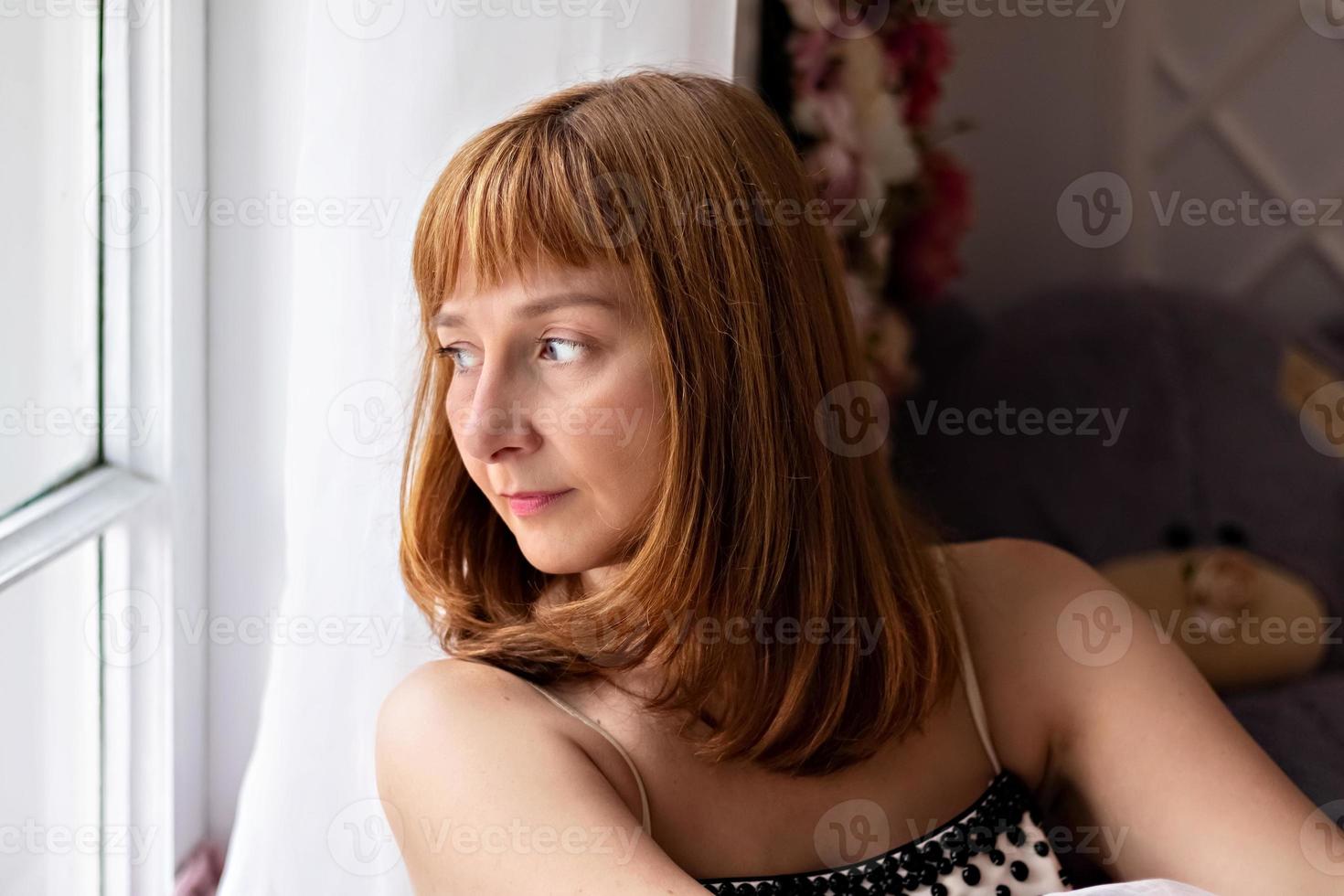 porträtt av en vacker ung kvinna som sitter vid fönstret. närbild foto